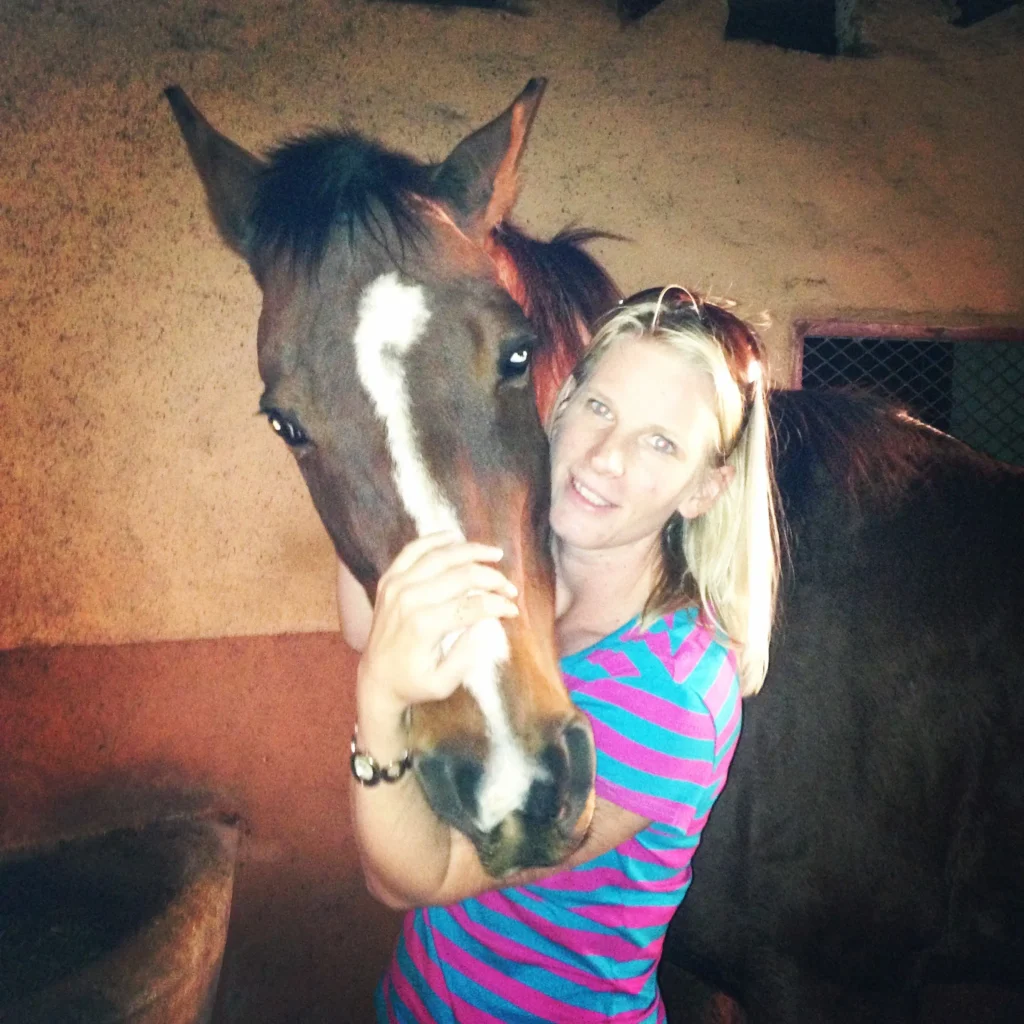blonde girl and bay horse with a white blaze on its face, looking at the camera