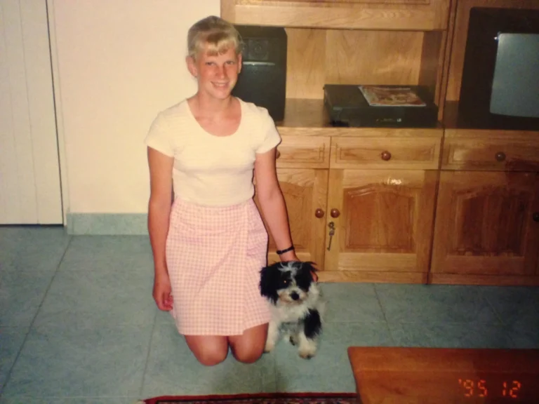 a young blond girl kneeling with a little black and white dog next to her