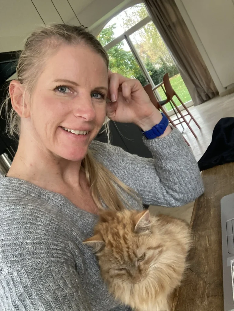 pet bereavement coach Sandra lynne Mitchell, a blond women sitting at a table with a giner cat